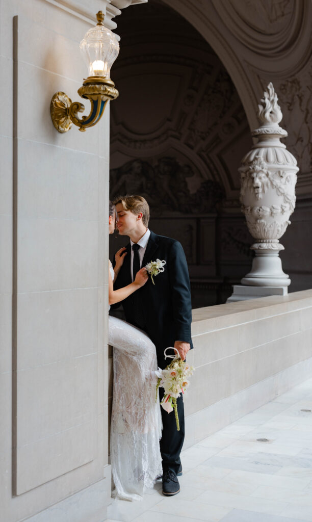 Groom kissing the bride and holding her flowers