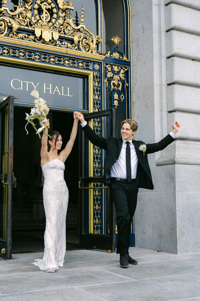 Bride and groom exiting the City Hall while holding hands