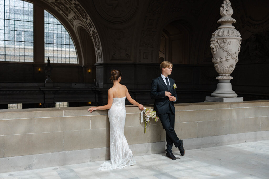 Bride and groom standing looking different directions on Mayor's Balcony